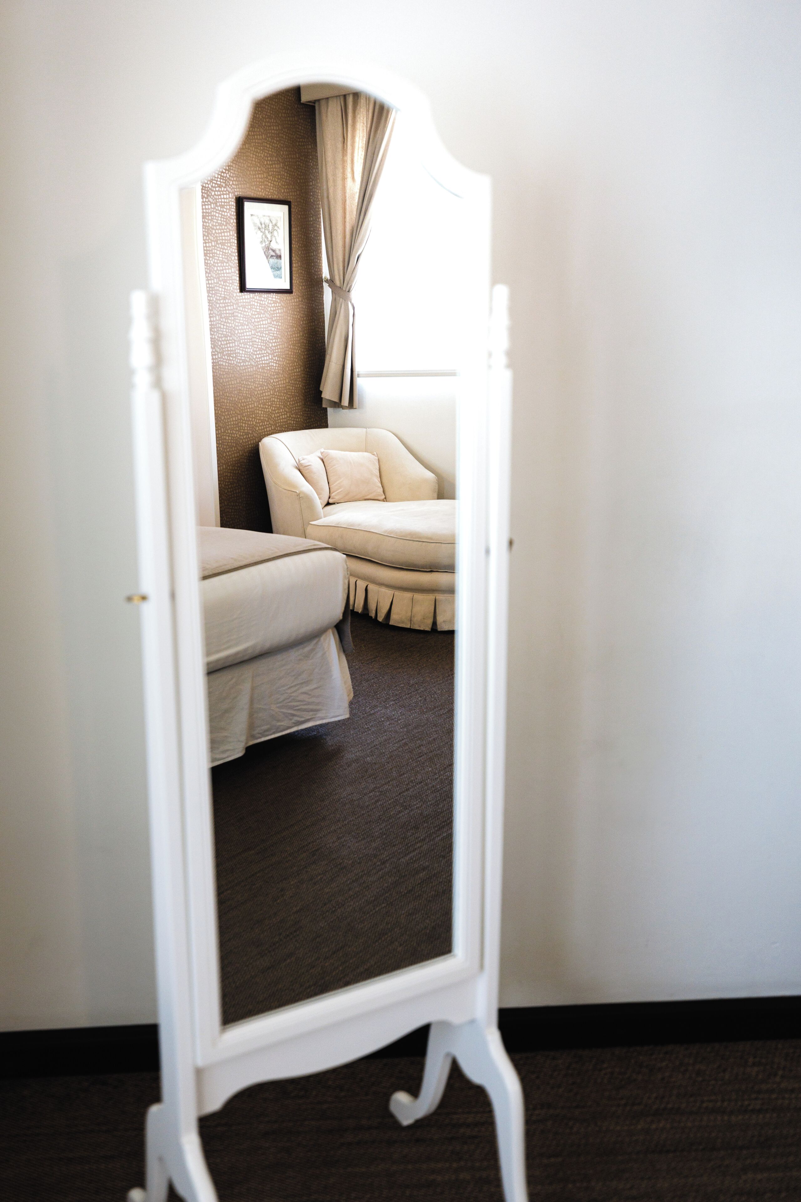 A room with a bed, a chair, and a mirror.