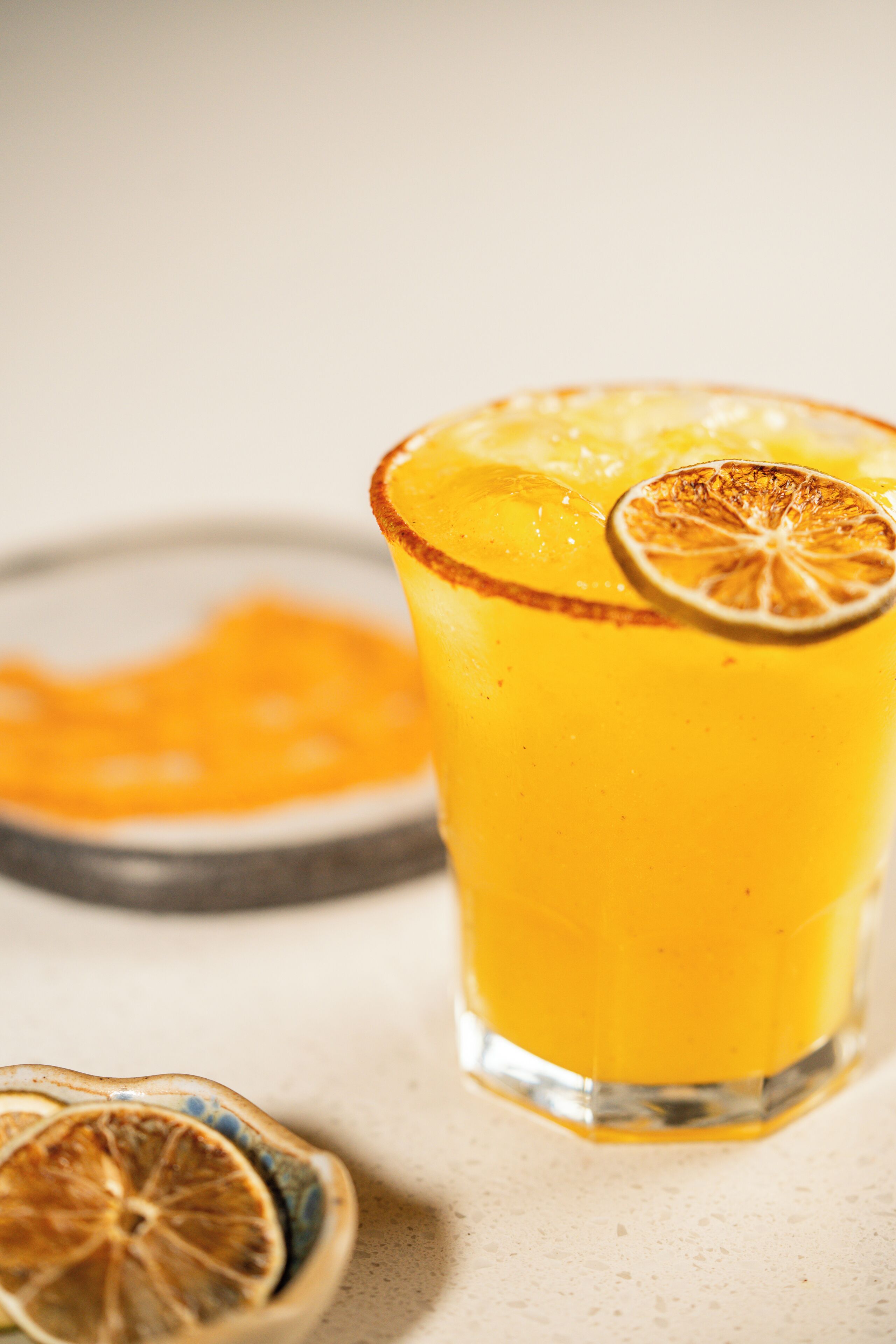 Un verre de jus d’orange, avec une tranche d’orange séchée sur le bord.