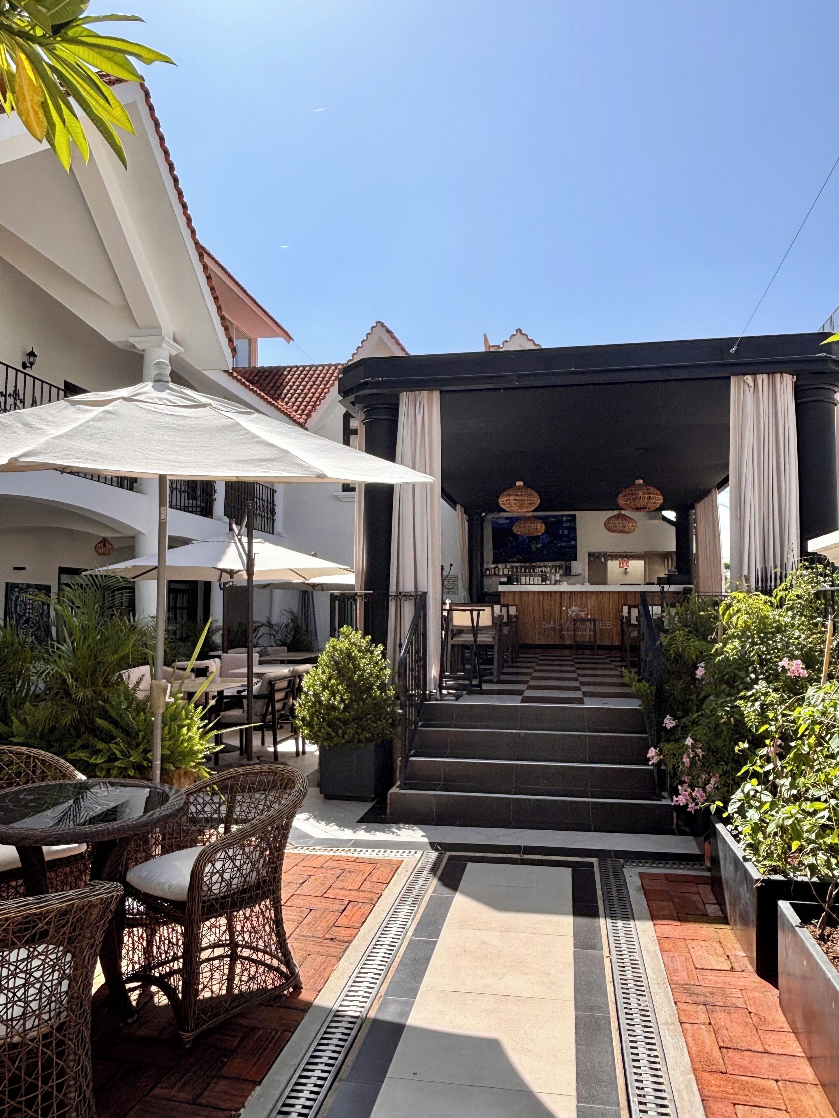 A covered outdoor seating area with wicker furniture and potted plants.