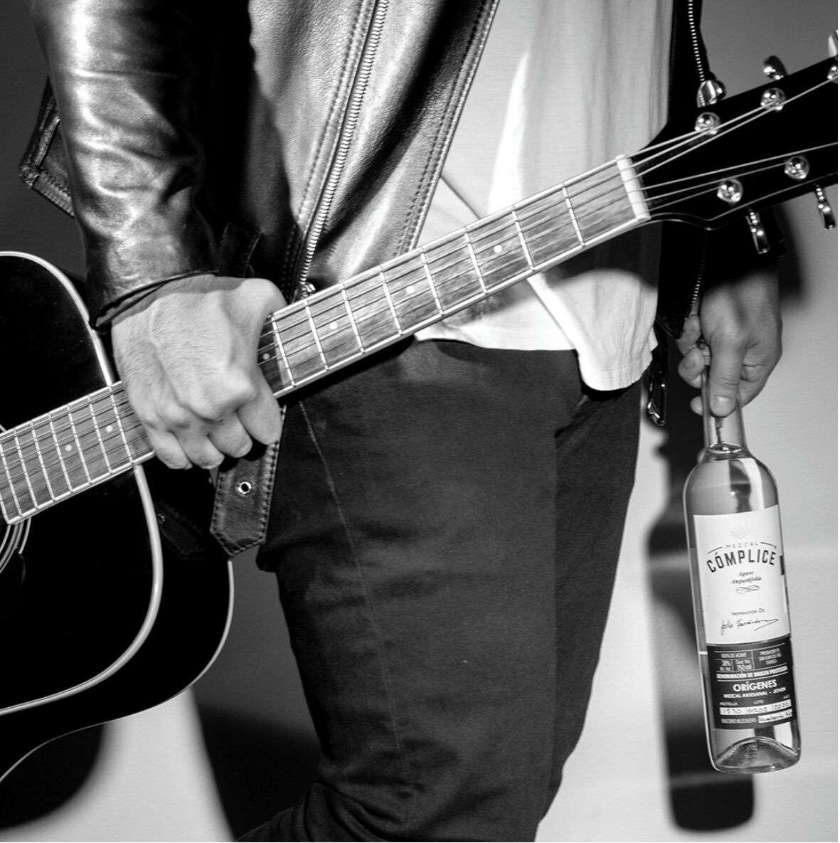 Una persona sosteniendo una guitarra y una botella de alcohol.