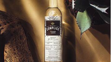 Una botella de mezcal con etiqueta que detalla su origen y añada.