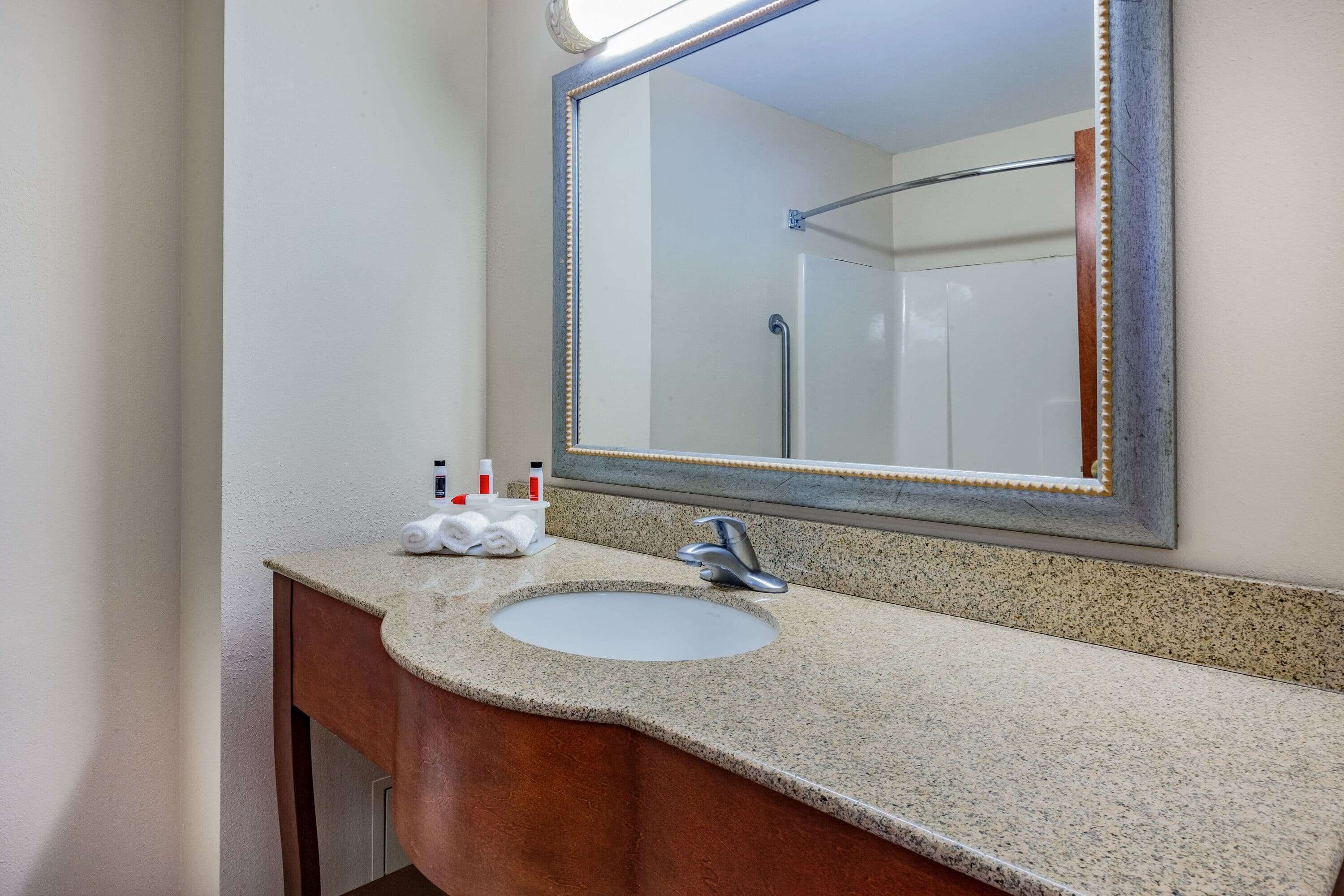 A bathroom with a granite countertop, a sink, a mirror, and a towel rack.