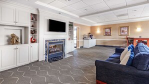 A spacious living room with a fireplace, a large sofa, and a television. - Days Inn by Wyndham Altavista (Altavista)