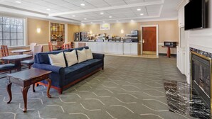 A hotel lobby with a sofa, dining area, kitchen, and fireplace. - Days Inn by Wyndham Altavista (Altavista)