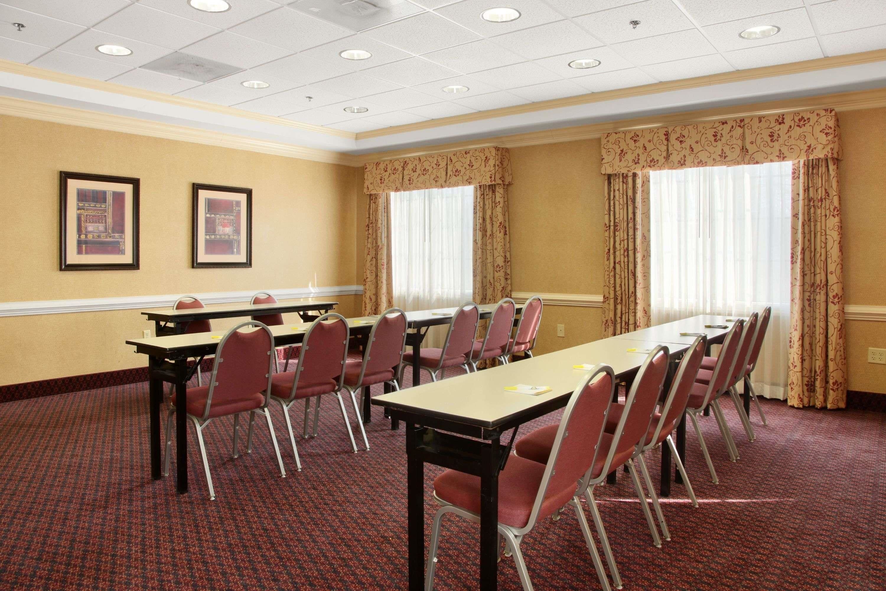 A conference room with a long table, red chairs, and two framed pictures on the wall.