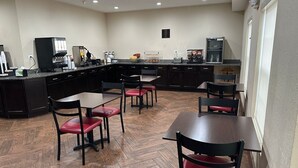 A modern kitchen with dark cabinetry, a central island, and a seating area with red chairs.