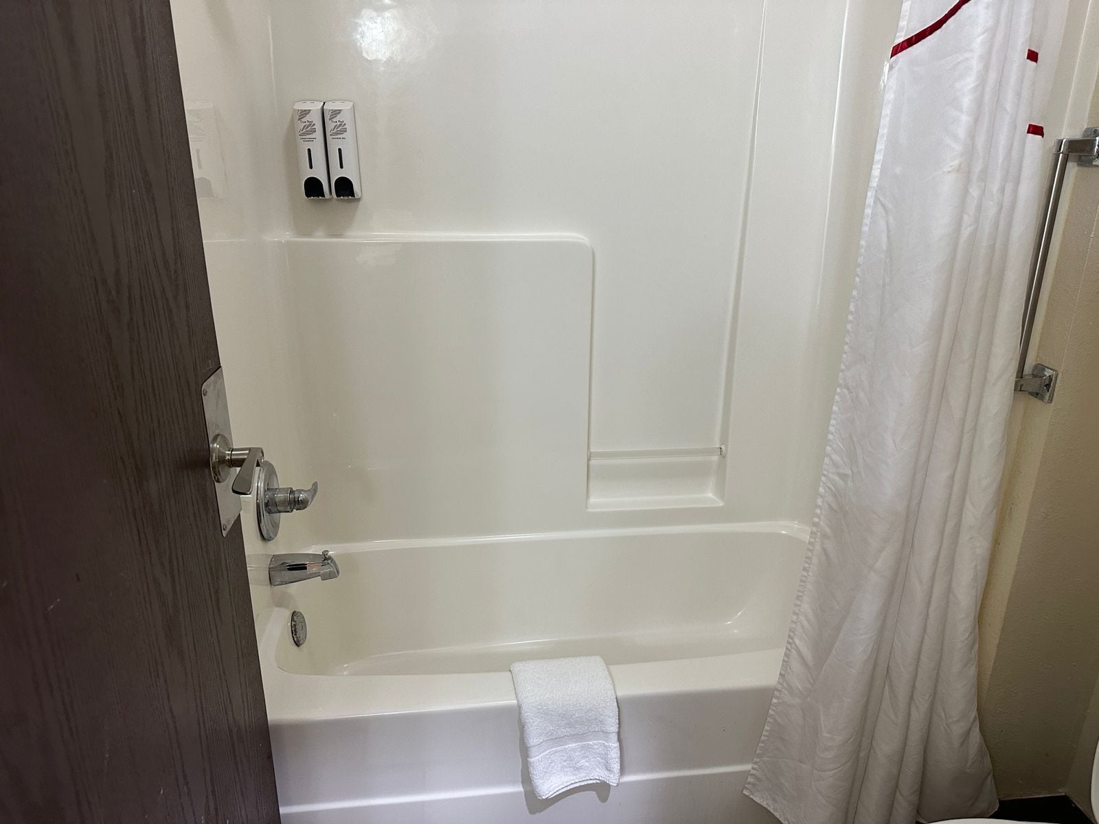 A bathroom with a bathtub, a towel rack, and a shower curtain.