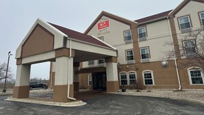 A multi-story building with a covered entrance, a sign indicating it's an EcoLodge, and a parking lot with a few cars.