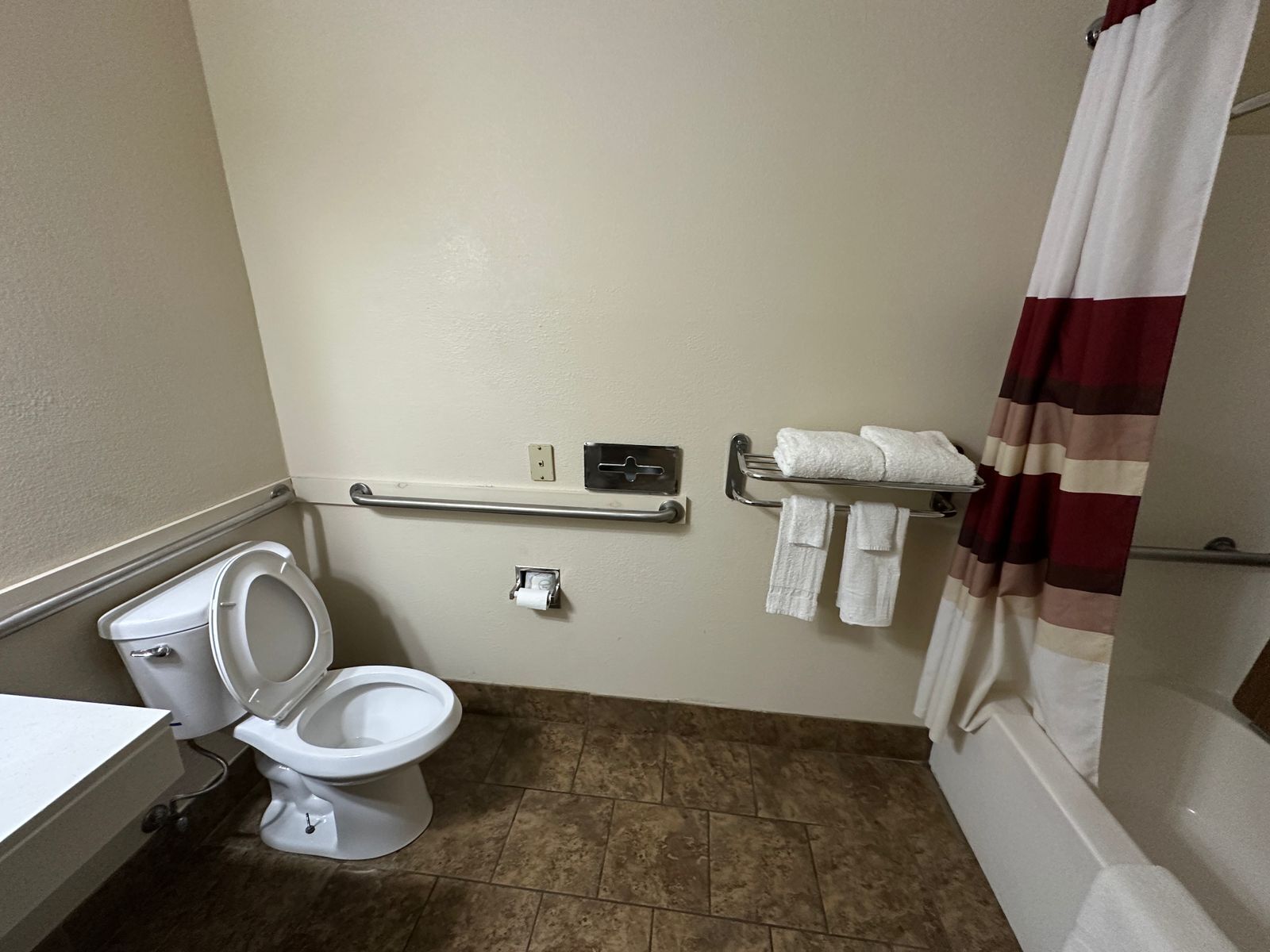 A standard bathroom with a toilet, a towel rack, and a shower curtain.