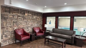 A lobby with a stone wall, a pool view, a sofa, two armchairs, and a coffee table.