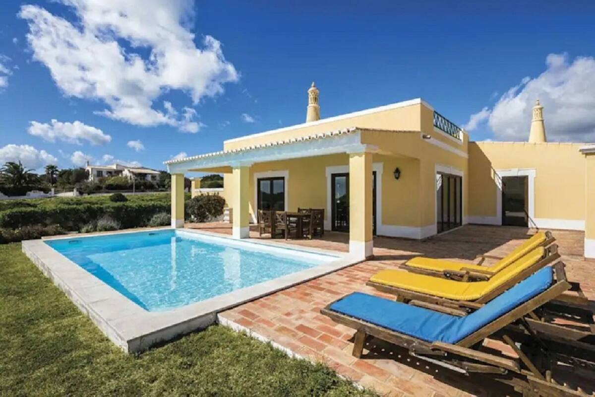 A poolside area with a pool, lounge chairs, and a covered seating area.