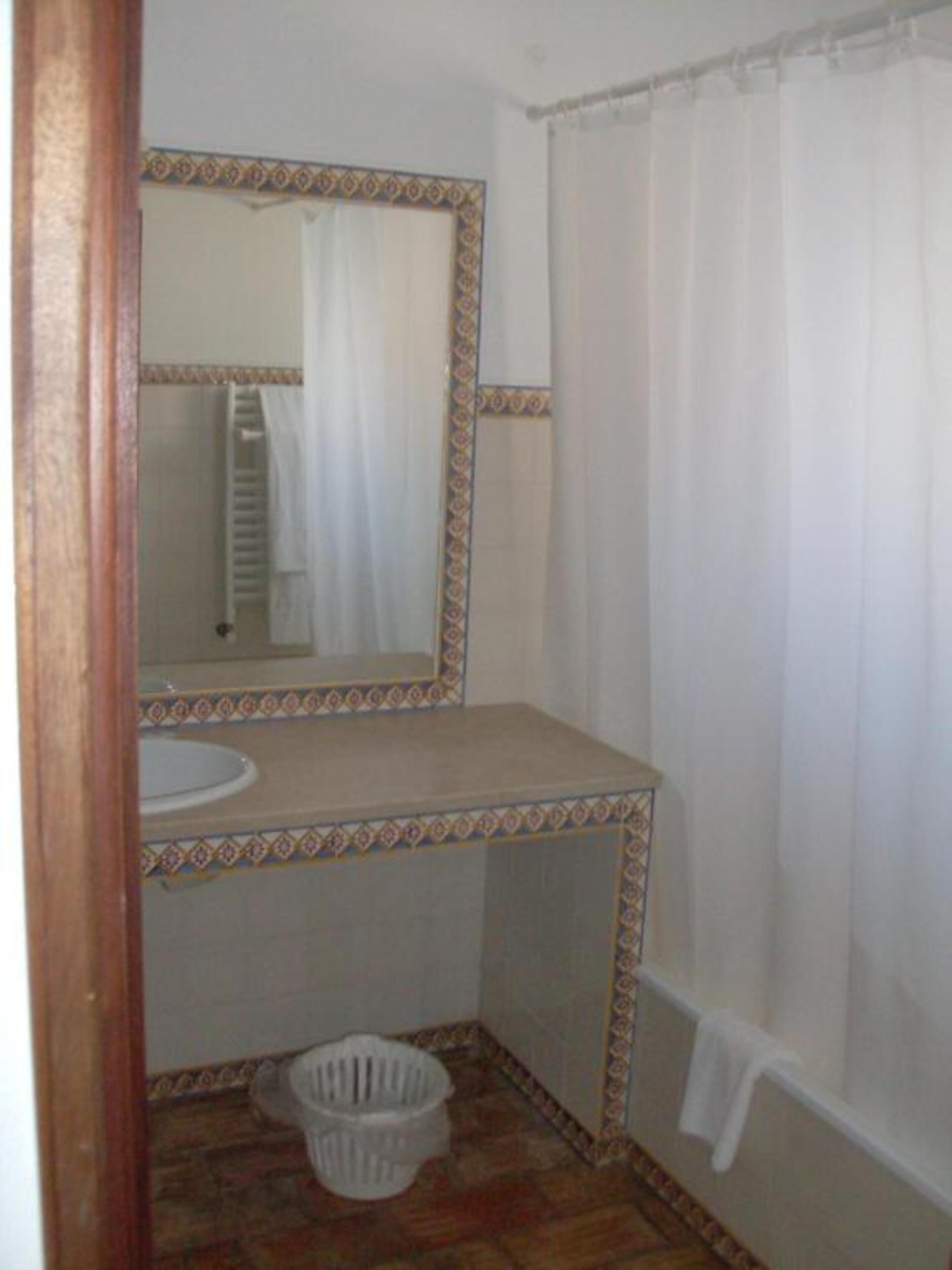Un baño pequeño con lavamanos, espejo y cortina de ducha.
