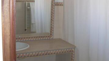 Un baño pequeño con lavamanos, espejo y cortina de ducha.