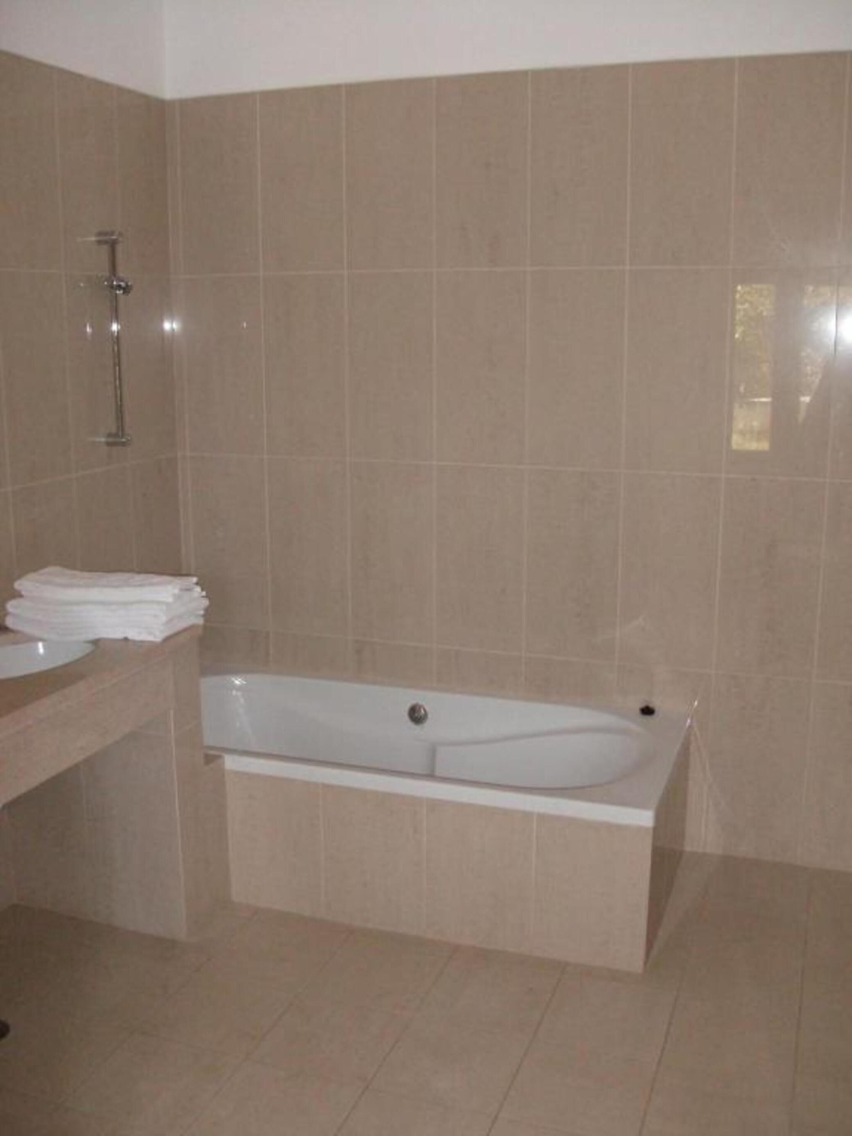 Une salle de bain avec une baignoire, un lavabo et un miroir.