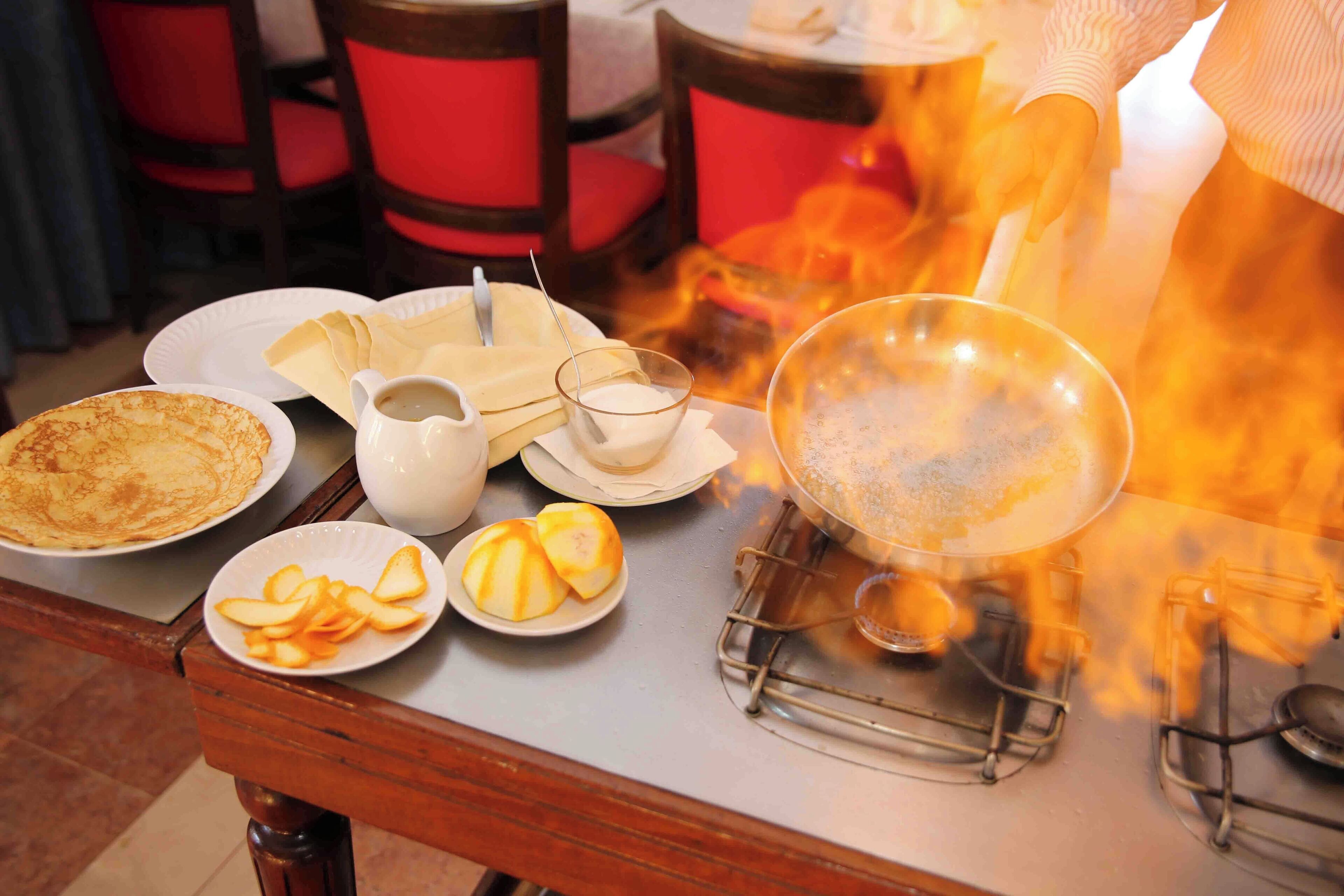 Una mesa con platos de comida, una taza y una sartén sobre fuego abierto.