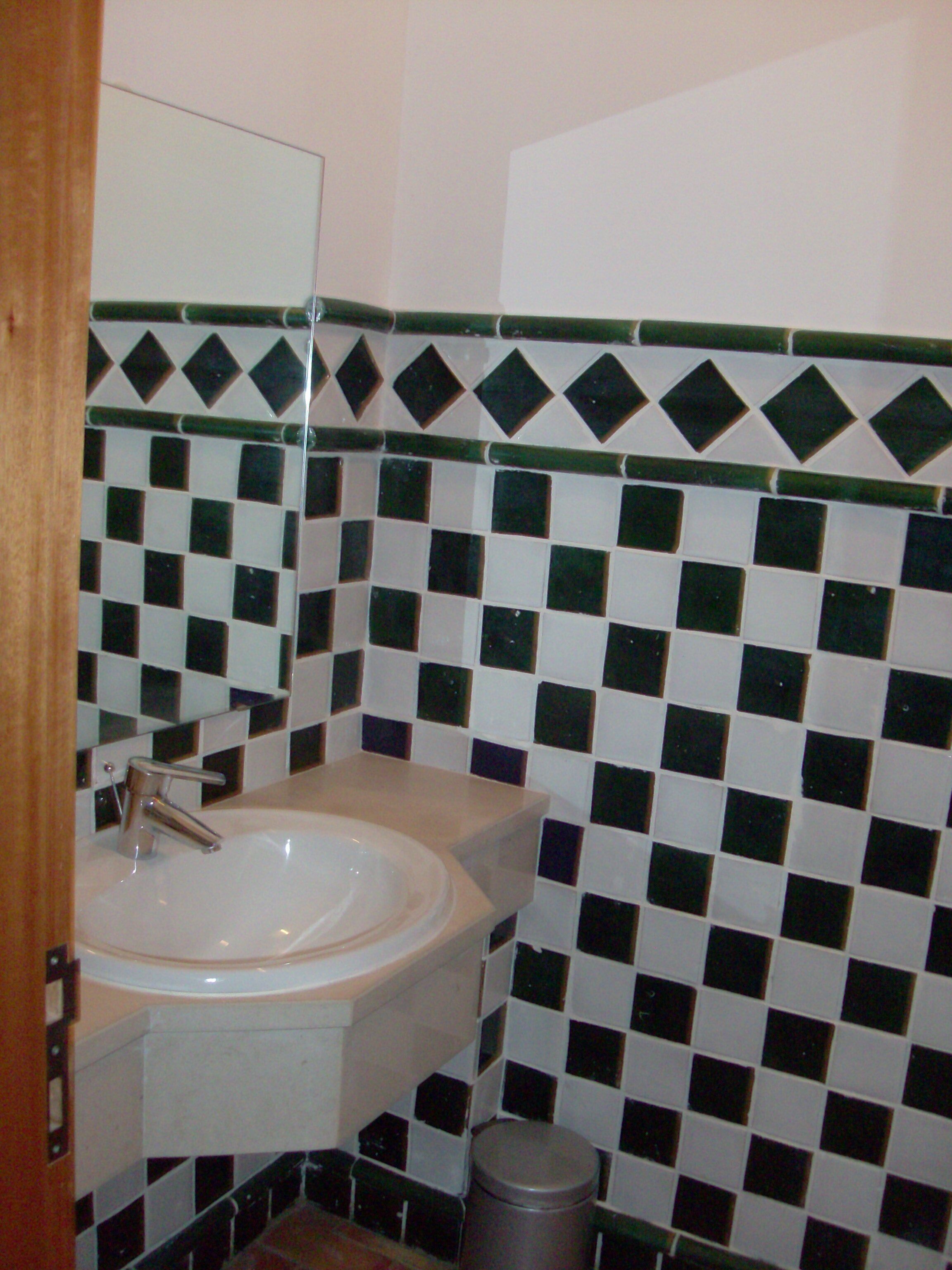 Un baño con lavamanos, espejo y paredes con azulejos.