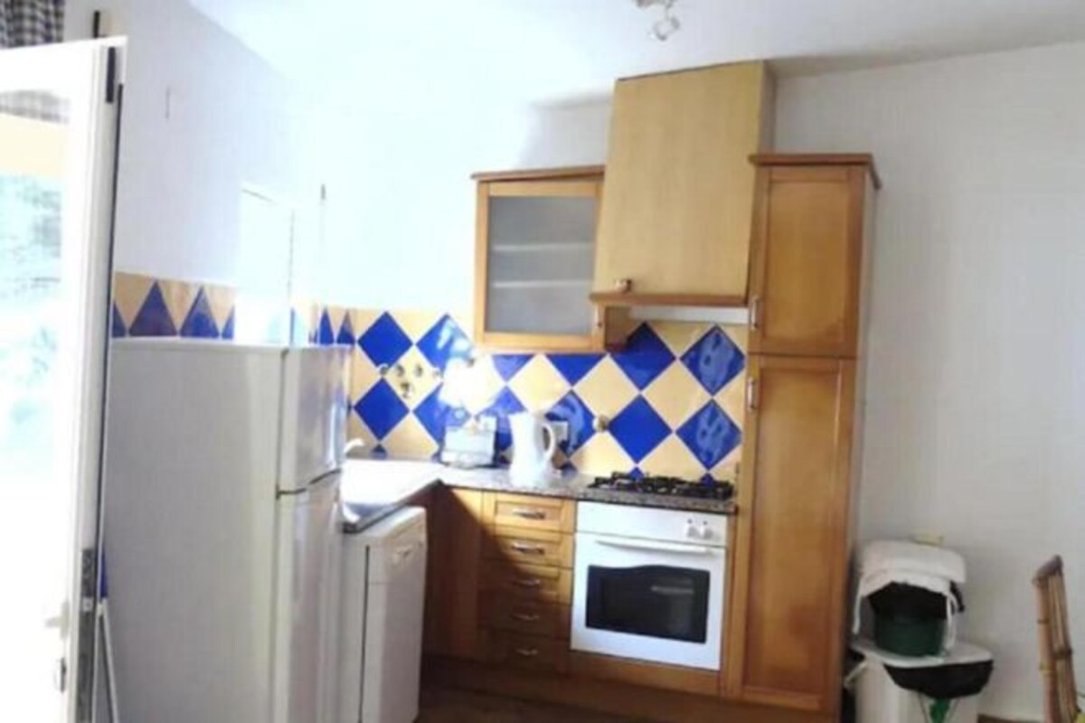 A compact kitchen with a refrigerator, stove, oven, and wooden cabinets.