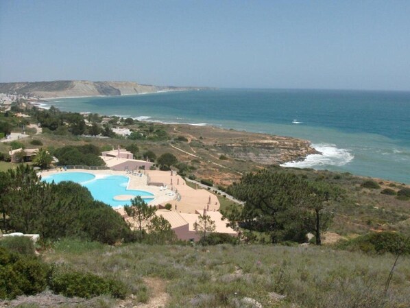 A coastal resort with a large pool, beachfront villas, and a view of the ocean.