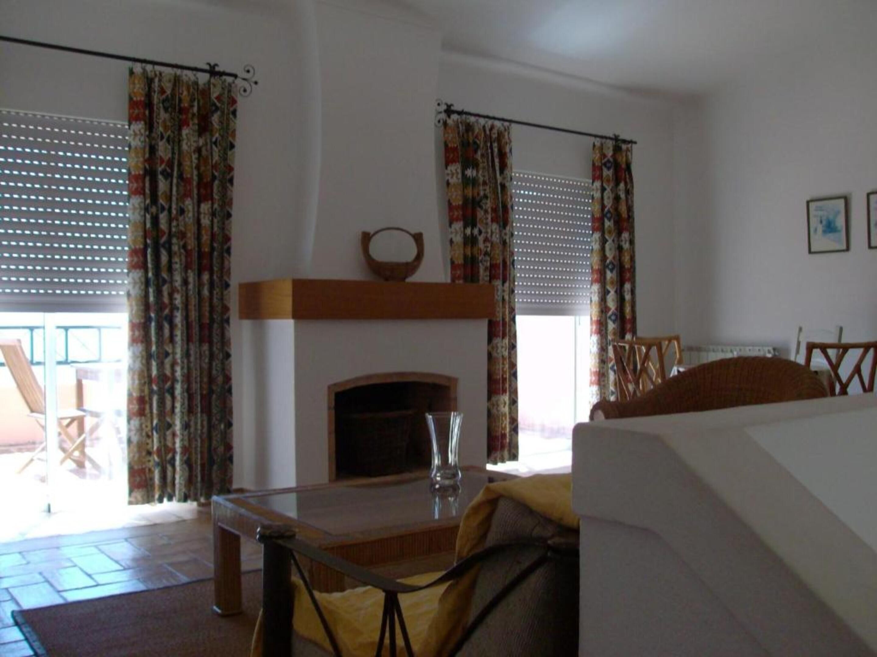 Una habitación con chimenea, cortinas, una mesa y una cama.
