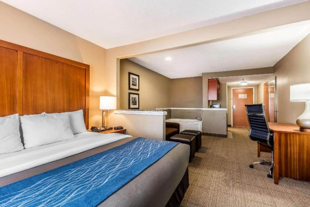 Habitación de hotel con cama, escritorio, silla y una pequeña área de kitchenette.