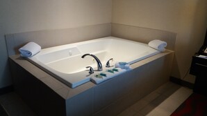Une salle de bain moderne avec une grande baignoire, deux robinets et un ensemble de produits de toilette disposés sur le côté.