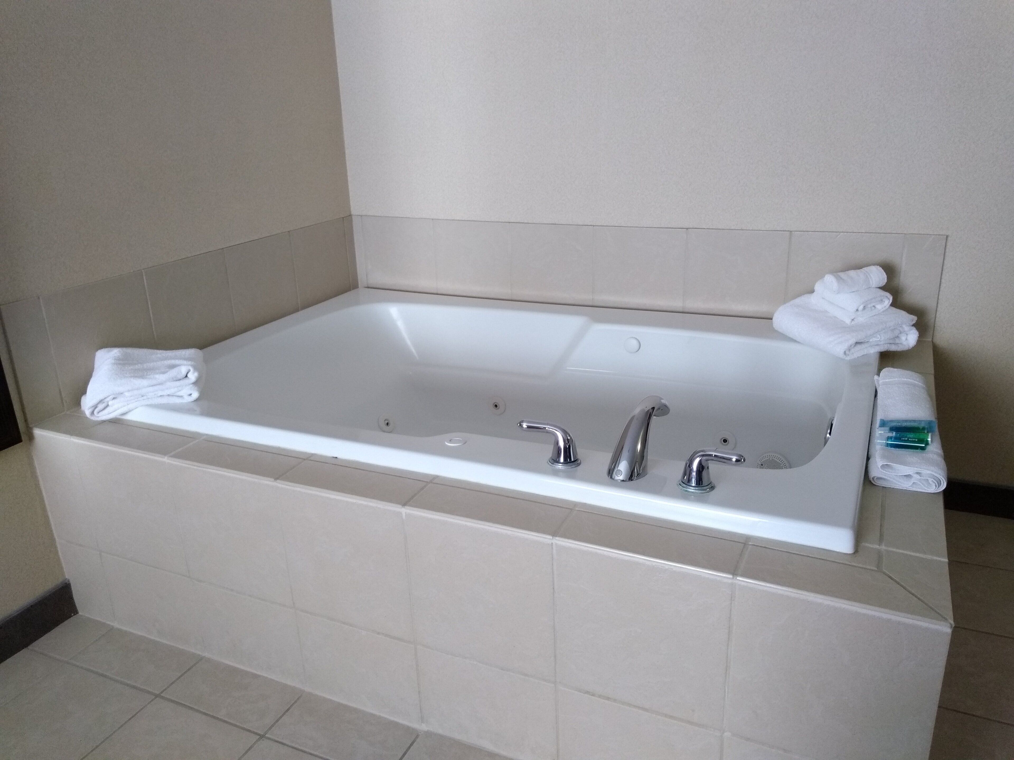 A hotel bathroom with a large bathtub, two faucets, and a towel rack.