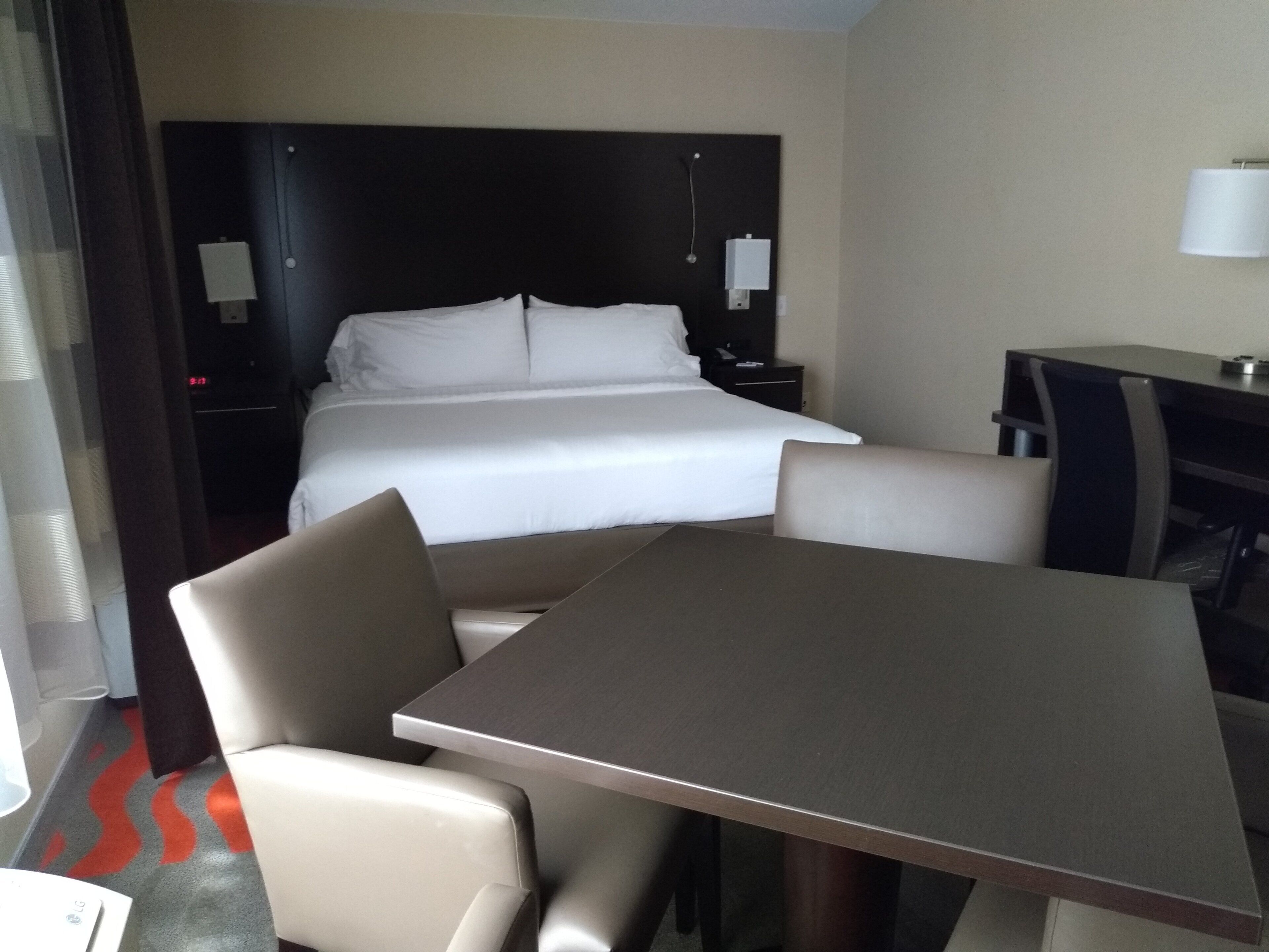 A hotel room with a bed, a desk, a chair, and a table.
