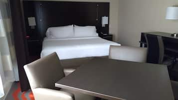 A hotel room with a bed, a desk, a chair, and a table.