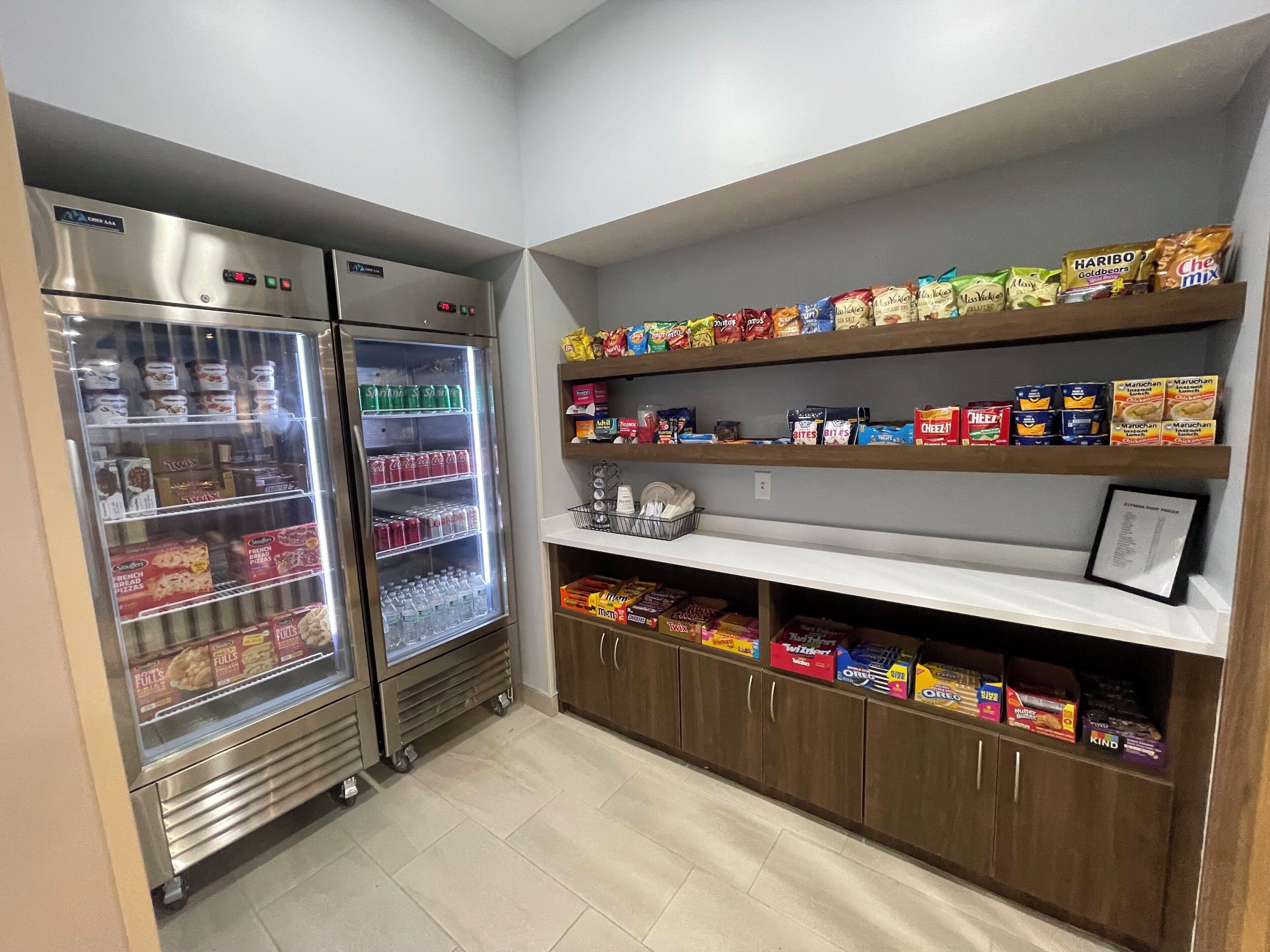 A snack and beverage refrigerator with a variety of items, including bottled water, soda, and snacks.