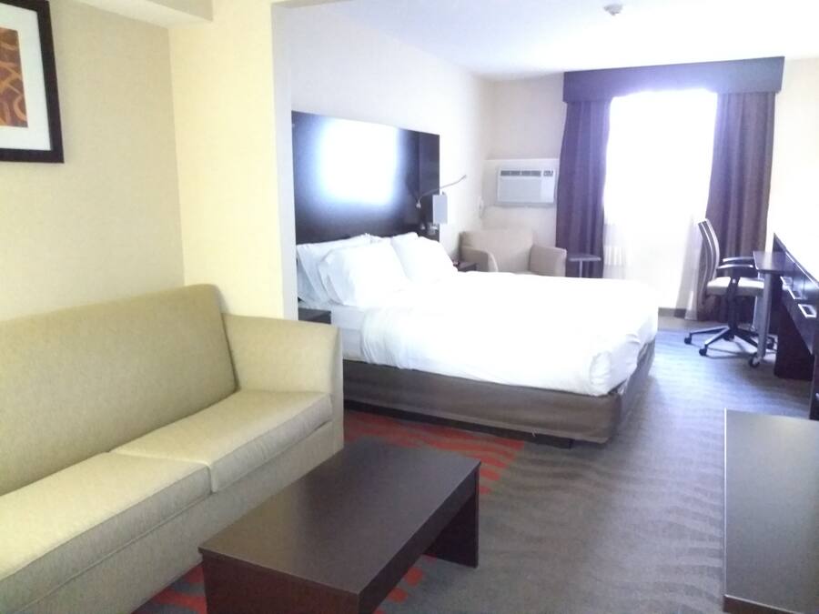 Une chambre d’hôtel avec un lit, un canapé, un bureau et une télévision.
