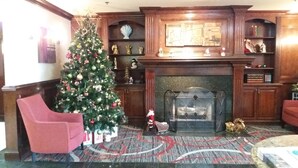 Un salon avec un sapin de Noël, une cheminée et des fauteuils rouges.
