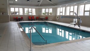 An indoor swimming pool with clear water, surrounded by red chairs and tables, and large windows allowing natural light. - Holiday Inn Express Hotel & Suites Waterford by IHG (Waterford)