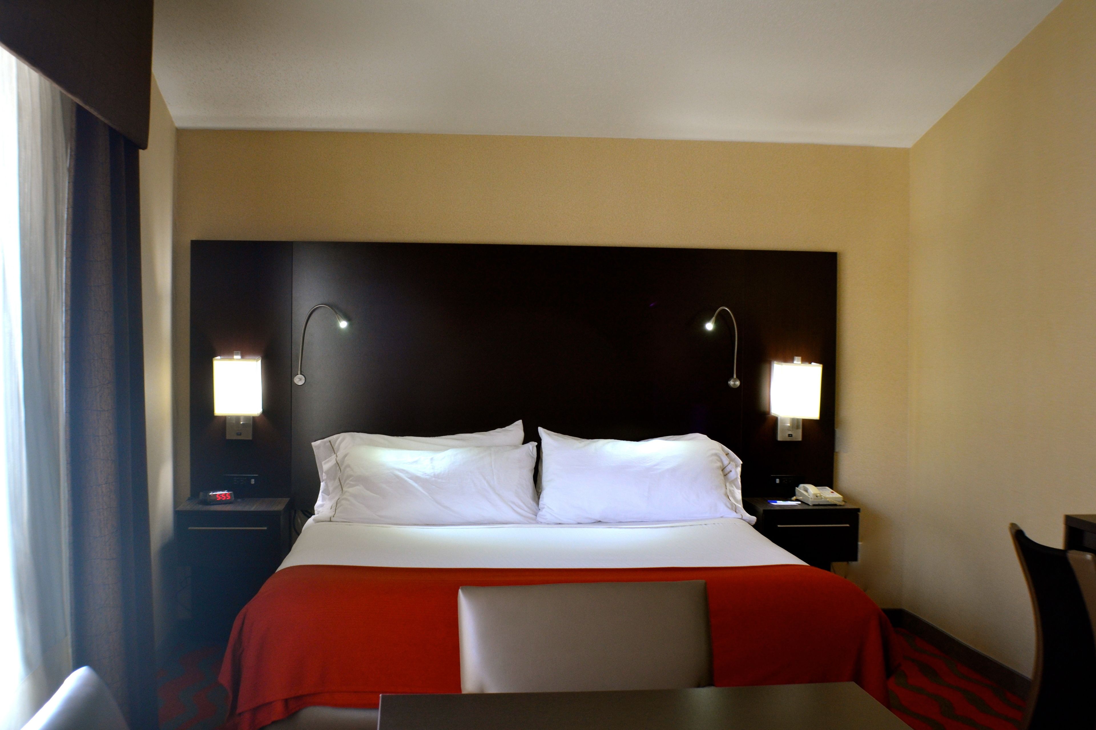 Una habitación de hotel con cama, lámparas de noche, un escritorio y una silla.