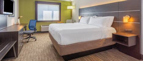 Una habitación de hotel con cama, escritorio, silla, televisor y ventana con persianas.