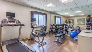 Ein Fitnessraum mit Trainingsgeräten, Laufband und Hantelbank.