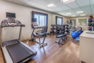 Un gimnasio con equipo de ejercicio, cinta de correr y banco de pesas.