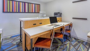 Ein moderner Arbeitsplatz mit Schreibtisch, Computer, Drucker und einem farbenfrohen abstrakten Gemälde an der Wand.
