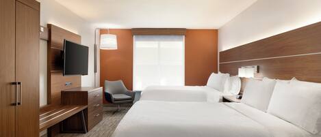 A hotel room with a large bed, a desk with a flat-screen TV, a chair, and a window with blinds.