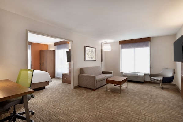 Una habitación de hotel con una cama, un sofá, un escritorio, una silla y una ventana.