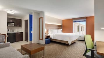 A hotel room with a bed, a desk, a chair, a kitchenette, and a bathroom.