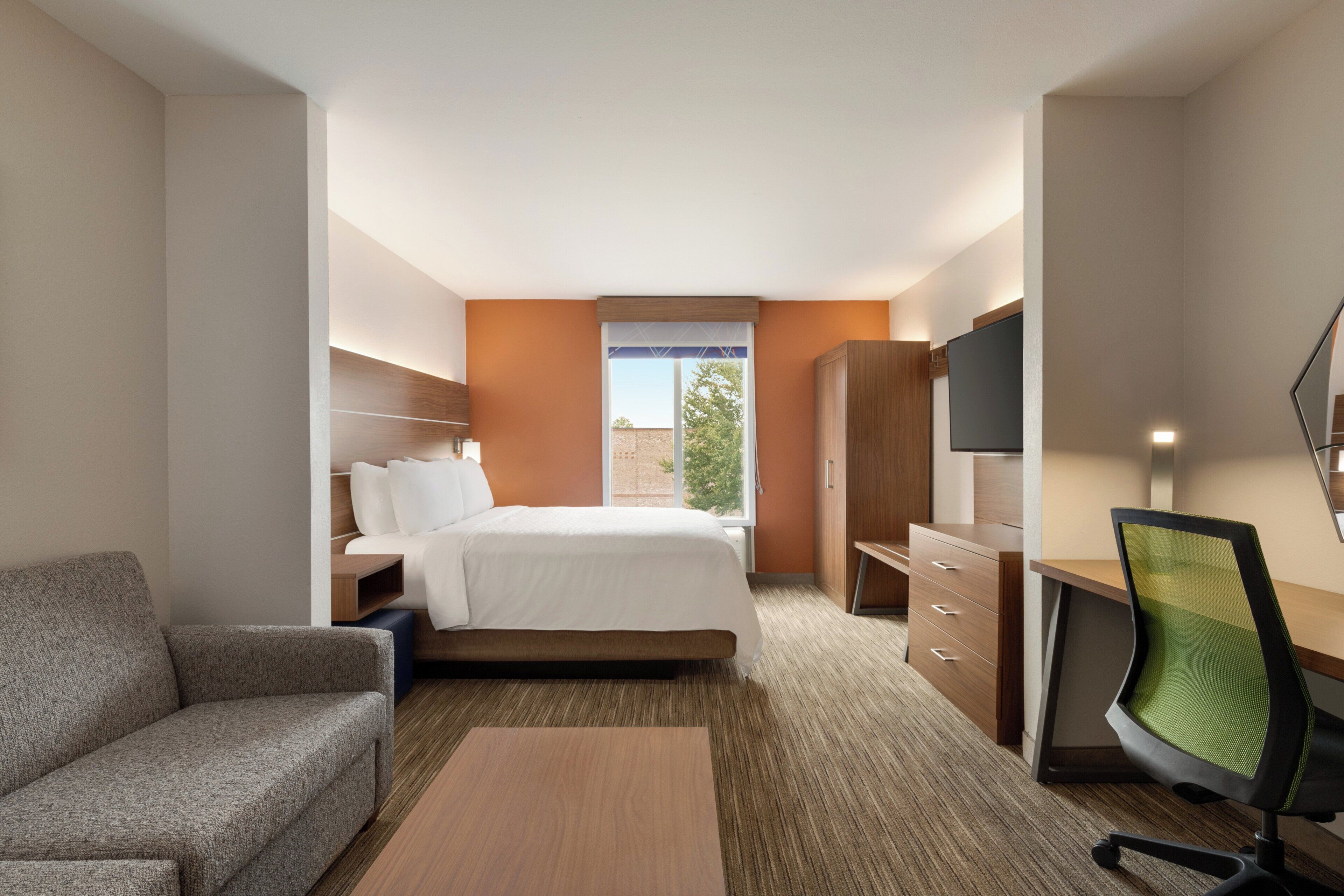 Une chambre d’hôtel comprenant un lit, un bureau, une chaise, un canapé et une armoire.