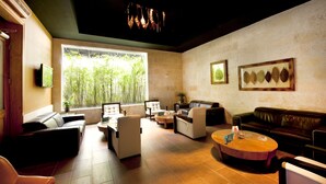 Un'ampia zona relax con divani in pelle, un tavolino rotondo e una grande finestra che si affaccia su una vegetazione di bambù.