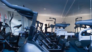 A gym with stationary bikes, weight machines, and a mirrored wall.