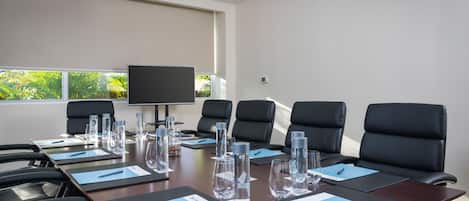 A conference room with a long table, black chairs, water bottles, and name cards.