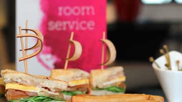A sandwich with toothpicks shaped like dollar signs, a sign with "room service" written on it, and a cup with toothpicks.