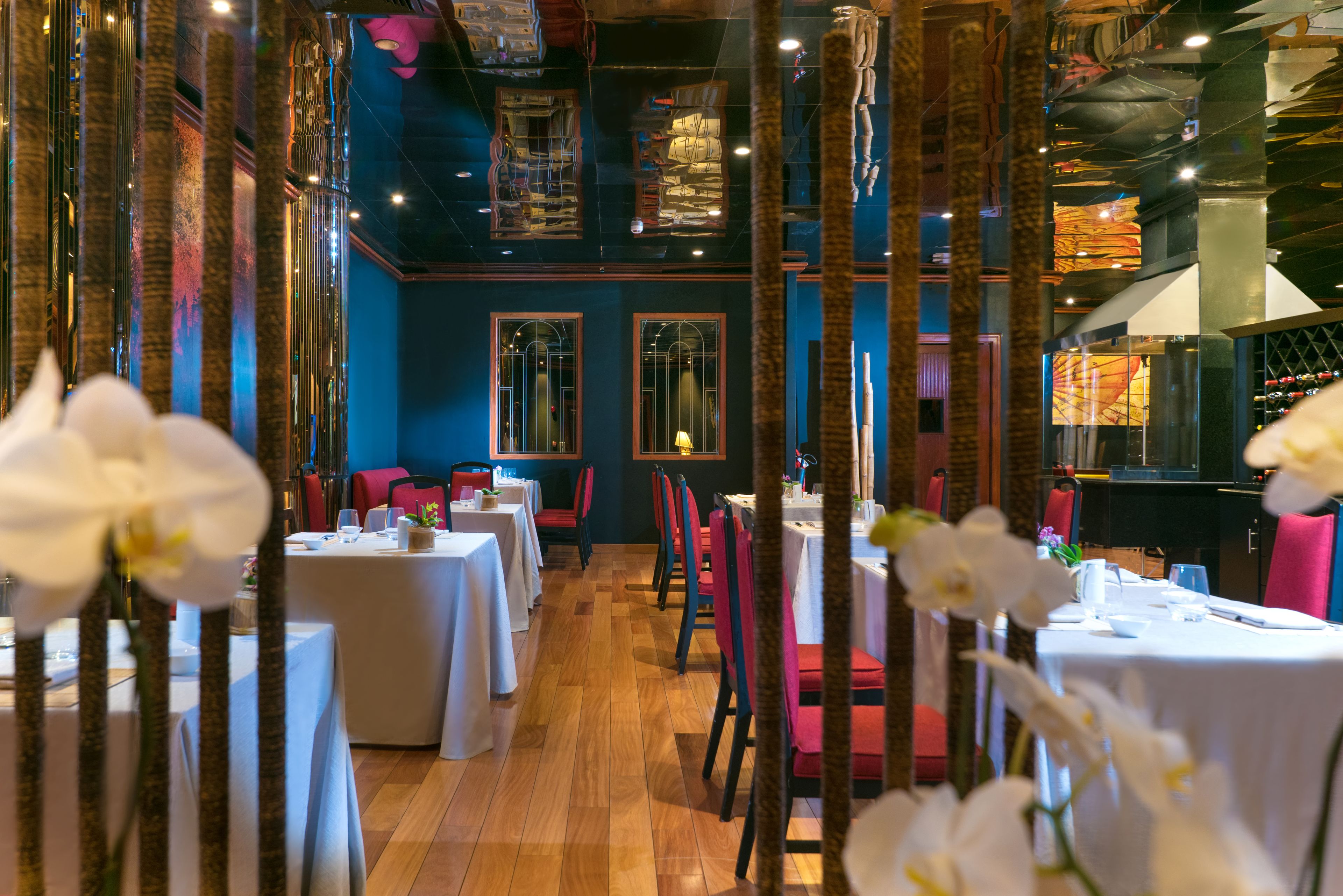 Un ristorante con diversi tavoli e sedie, pavimento in legno ed elementi decorativi come orchidee.