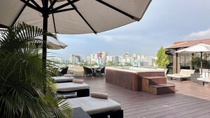 Una terrazza panoramica con posti a sedere all'aperto, una vasca idromassaggio e vista sulla città.