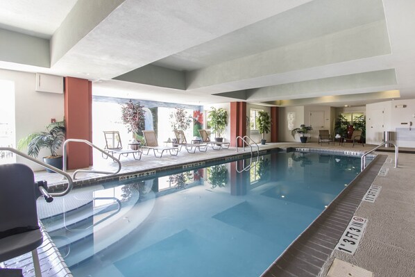 An indoor swimming pool with clear water, surrounded by lounge chairs and potted plants. - Holiday Inn Express Hotel & Suites Cullman by IHG (Cullman)