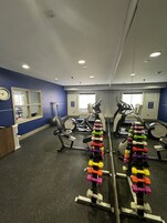 Un gimnasio con diversos equipos de ejercicio, incluyendo pesas y máquinas de cardio.