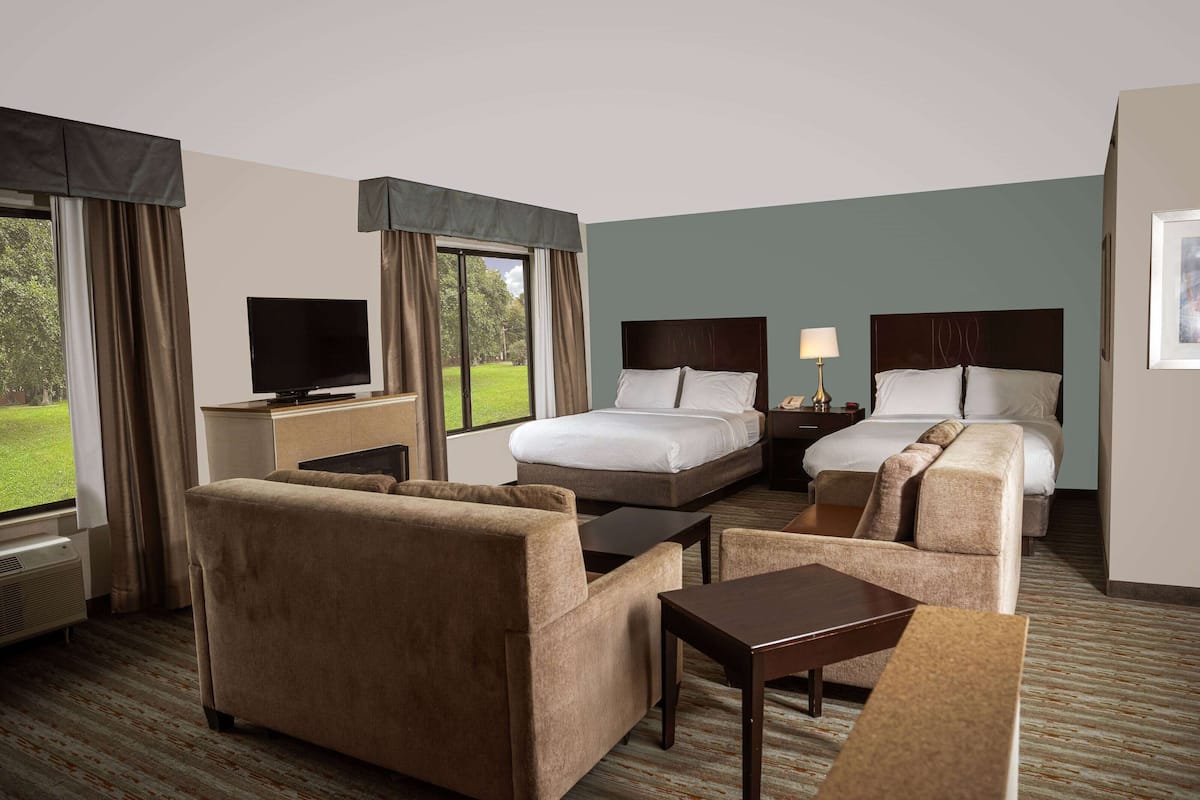 A hotel room with two beds, a TV, a desk, and a sofa.